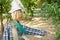 Straw and wood scarecrow dressed in plaid shirt with raised hand and gloves in the shadow of the botanical garden