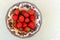 Strawberries in antique bowl isolated on green and white tablecloth from above.