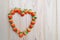 Strawberries array heart shape on wooden table with copy space