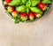 Strawberries with basil leaves in gray dish on beige table, top view, close up