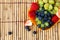 Strawberries, blueberries and grapes on a bamboo mat