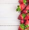 Strawberries border on white old wooden table