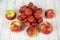 Strawberries of bright red color in a pile on a plate with apples on a gray wooden table.