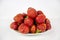 Strawberries of bright red color in a pile on a plate isolated on a white background