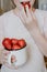 Strawberries in children hands. Girl child holding fresh red organic strawberries in white enameled cup. Summer vitamins