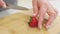 strawberries are cut into pieces on a wooden cutting board to decorate desserts.