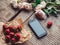 Strawberries, flowers and phone on the rustic table. Healthy breakfast, Clean eating, vegan food concept.