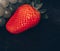 Strawberries and grapes on a black background, place for an inscription, fruits isolated with copy space.