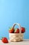 Strawberries in Small Basket against Blue Background