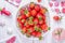 Strawberries in white ceramic bowl and pink strawberry milkshake or cocktail