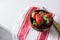 Strawberries in wooden bowl on dishtowel, red and white stripes