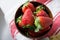 Strawberries in wooden bowl on dishtowel, red and white stripes