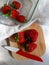 Strawberries on wooden cutting board, kinfe and glass container on white linen napkin.