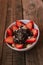 Strawberries with yogurt chocolate pumpkin seeds chia sunflower seeds and apple in a white bowl on a wooden table