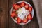 Strawberries with yogurt seeds pumpkin seeds chia sunflower seeds and apple in a white bowl on a wooden table