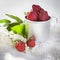 The Strawberry in an aluminum cup, white lilac on a white napkin on a white wooden table