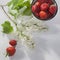 The Strawberry in an aluminum cup, white lilac on a white napkin on a white wooden table