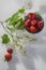 The Strawberry in an aluminum cup, white lilac on a white napkin on a white wooden table