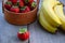 Strawberry in a basket and bananas on a wooden background. Ingredients for smoothies, yoghurt, cocktail. Yogurt with fresh strawbe