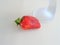 Strawberry on a beige background at the foot of the glass