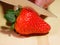 Strawberry being cut in half on wooden chopping board