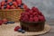 Strawberry and blueberry in basket and raspberries in bowl on wood table. Fresh berries