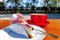 Strawberry cheesecake on an outdoor table along with a red coffee mug in the morning sunlight