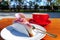 Strawberry cheesecake on an outdoor table along with a red coffee mug in the morning sunlight