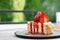 Strawberry cheesecake with strawberry slices on a gray ceramic plate.