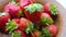 Strawberry on a clay plate covered with water droplets are spinning. Camera pulls back from the berries.