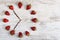 Strawberry clock with arrows of coffee beans showing a time of six or eighteen hours fifty-five minutes on an old board