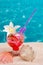 Strawberry cocktail on beach sand with seashells