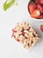 strawberry crumb bars with fresh red berries in a cup and strawberry buch with flowers on grey background