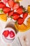 Strawberry cut in half, orange sliced â€‹â€‹jars of yogurt, two spoons on a wooden table