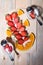 Strawberry cut in half, orange sliced â€‹â€‹jars of yogurt, two spoons on a wooden table