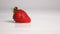 Strawberry drop on white wet surface