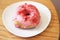 Strawberry-glazed with raspberry cream filling doughnut on a white plate