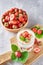 Strawberry granola or smoothie in a glass and fresh berries in wooden bowl, top view. Healthy breakfast