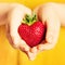 Strawberry in Hand. Red Berry Heart on Yellow Background