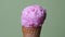 Strawberry ice cream scoop in waffle cone on green background.