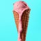 Strawberry ice cream on waffle cone melting. Blue background