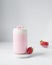 strawberry latte with cream in a can shaped glass on a marble coaster