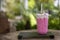 Strawberry milkshake  and fresh ripe berries on wooden table with green blurred natural background. Pink smoothie