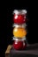 Strawberry, orange and raspberry jams in glass jars against the black background