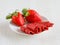 Strawberry pastille made from pure fruits in rolls and fresh berries on white plate.