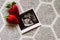 Strawberry and a photo of a human fetus from an ultrasound scan during pregnancy on a gray background