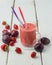 Strawberry plum smoothie in a glass with a straw.