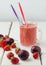 Strawberry plum smoothie in a glass with a straw.