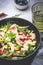 Strawberry, shrimp and herbs salad with arugula, lettuce, avocado and almond slices, gray table. Fresh useful dish for healthy