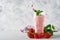 Strawberry smoothie or milkshake with berries and mint in tall glass on light grey background. Summer drink shake, milkshake and r